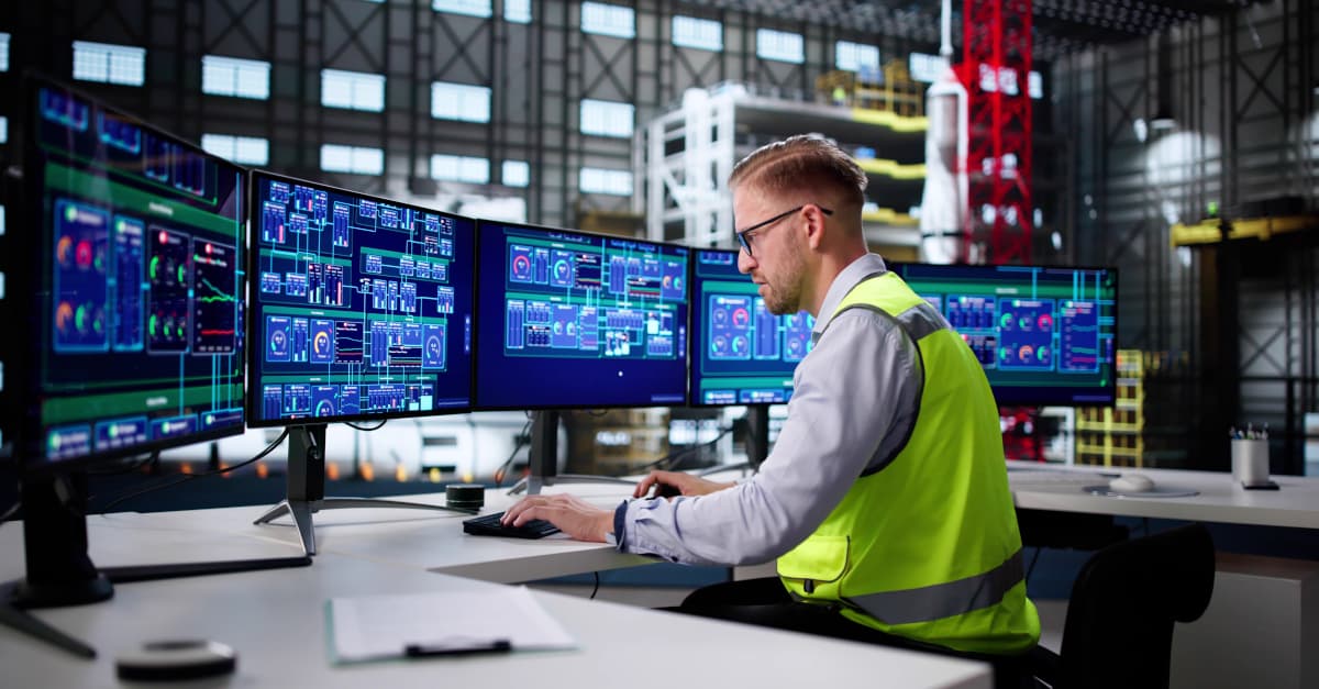 A rail control room at dusk with a dimly lit operator workstation, a wall of network status displays glowing cool blue, and a single alarm list panel highlighted in warm amber, suggesting a flood of alarms being brought back under control.